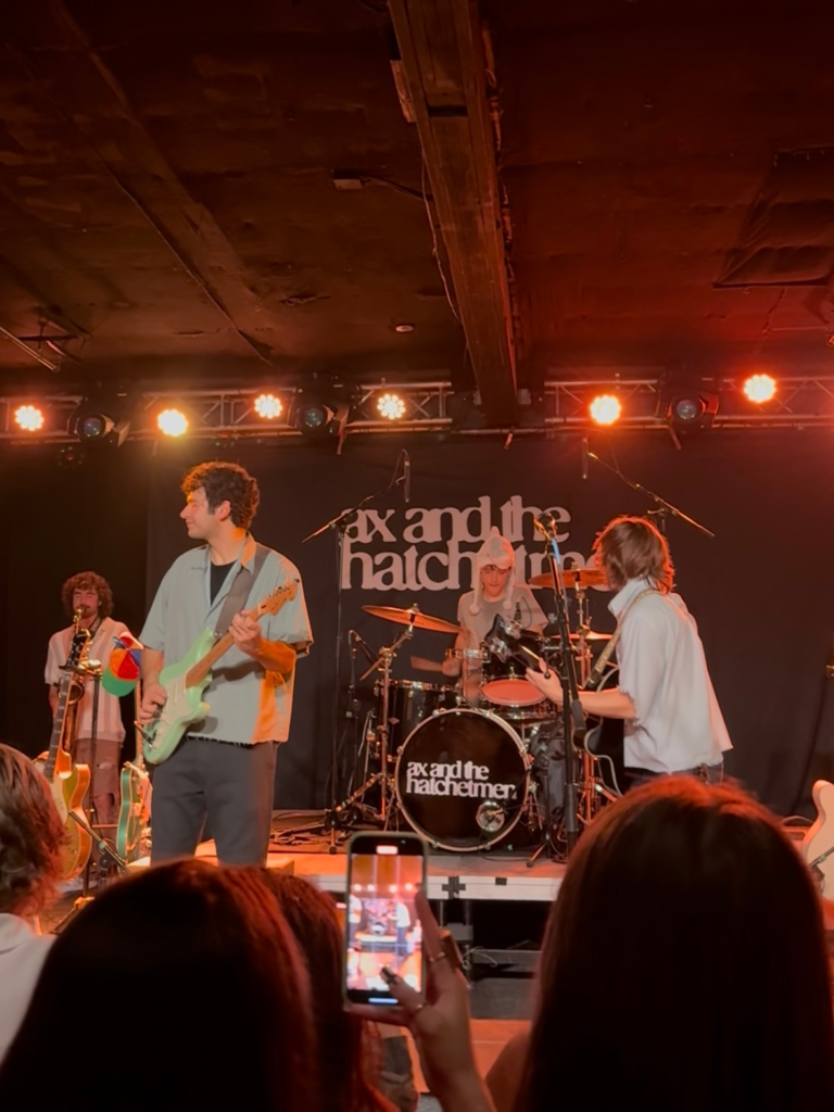 band onstage in small venue with orange lighting, playing song from new album