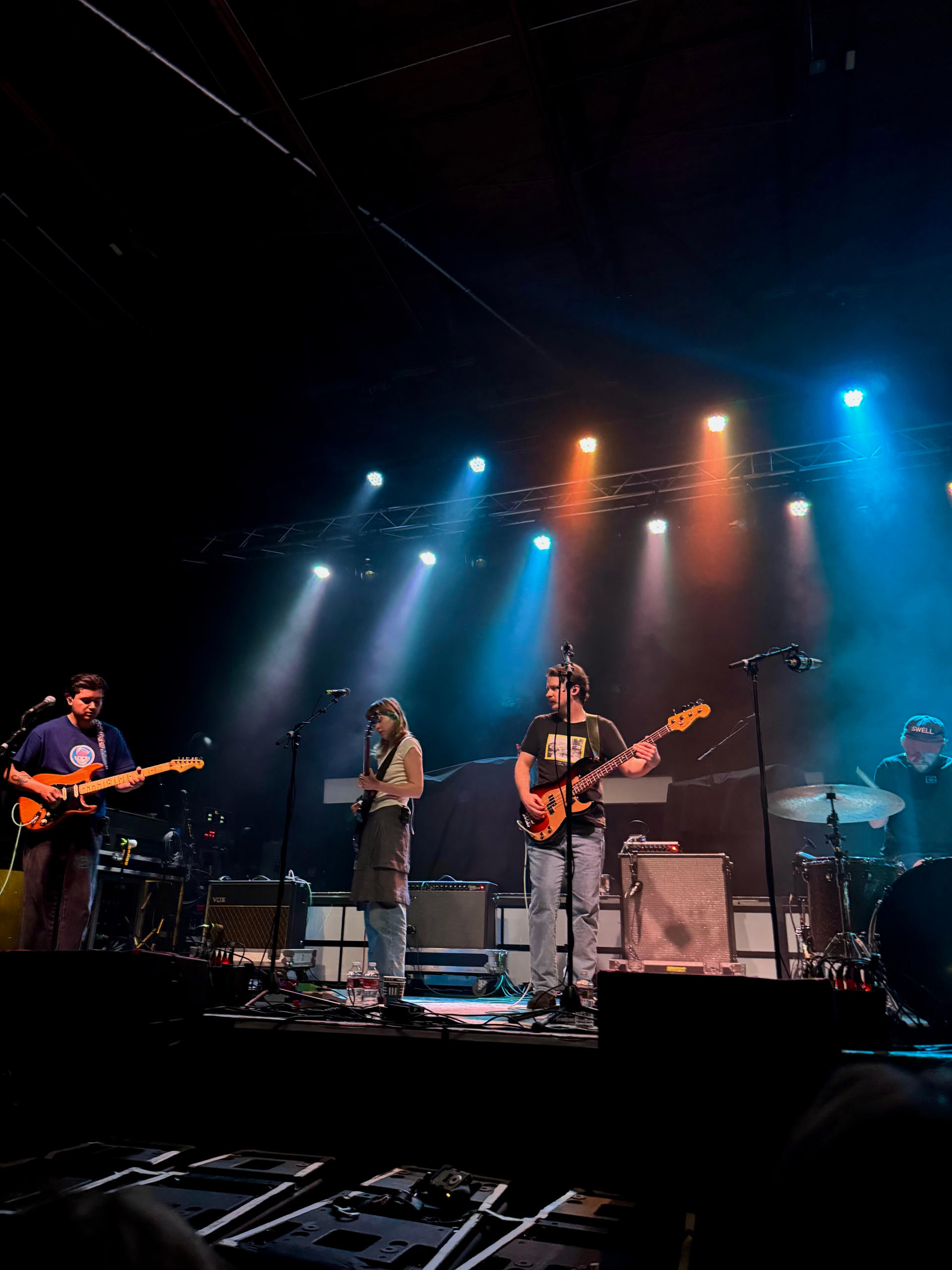 blue and orange lit stage, band onstage playing new album